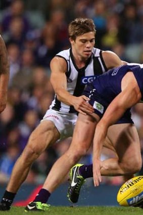 Zac Dawson of the Dockers looks to gather the ball while Josh Thomas of the Magpies looms.