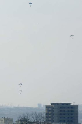 North Koreans soldiers are seen parachuting from a helicopter into the town of Sinuiju in this photo taken from the Chinese border city of Dandong.