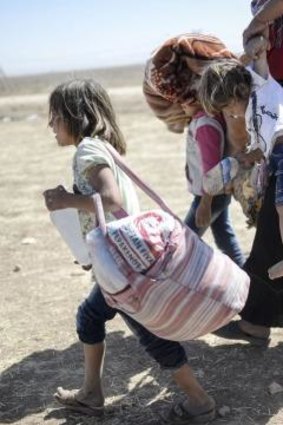 Syrian Kurds carry their belongings across the border into Turkey. Tens of thousands have fled the advance of Islamic State.