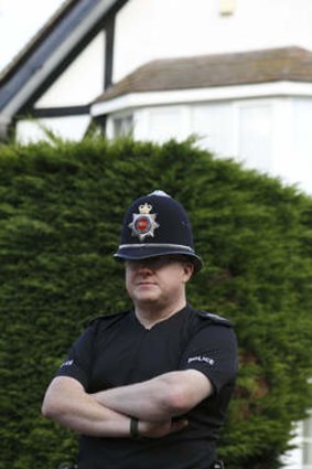 A police officer outside the family's home in Surrey, England.