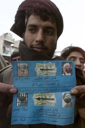 An Afghan shows leaflets dropped by US  planes along the Afghan-Pakistan border in March 2003 reading "Chase Murderers" and naming Osama bin Laden and Mullah Omar. Doubts later emerged over whether the second picture was indeed Mullah Omar's.