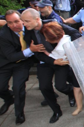 Former Prime Minister Julia Gillard is dragged away by her close protection team police to her car after hundreds of protesters from the Aboriginal Tent Embassy on Australia Day in 2012.