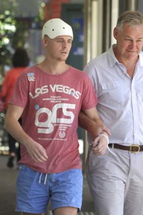 'Miraculous': Bashing victim Michael McEwen walks from St Vincent's Hospital on Monday with his father, Rob, by his side.