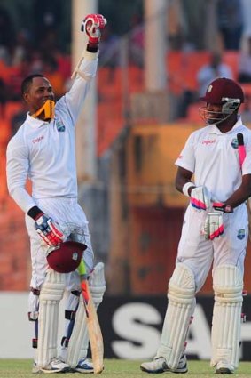 Marlon Samuels waves to his teammates in the pavilion, after reaching his hundred, as Darren Bravo looks on.