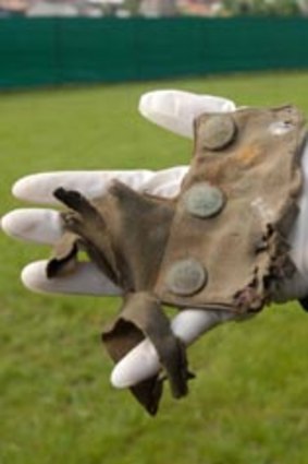 Exhumed...part of a soldier's uniform found on the site, using metal detectors,  top.