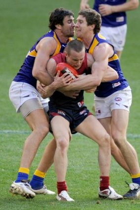 Patrick McGinnity (right) and West Coast teammate Josh Kennedy tackle Melbourne's Tom Scully during their match last weekend.