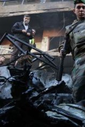 Lebanese soldiers and civilians inspect the scene of an apparent suicide car bombing in Beirut.