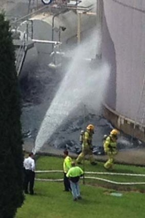 Emergency workers spray water on the chemical spill.