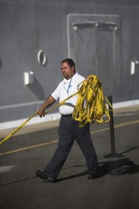 A West Indian Company employee removes a yellow caution barricade tape from around the Royal Caribbean International's Explorer of the Seas cruise ship.