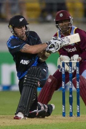 Luke Ronchi hammers a ball to the boundary as West Indies keeper Denesh Ramdin looks on.