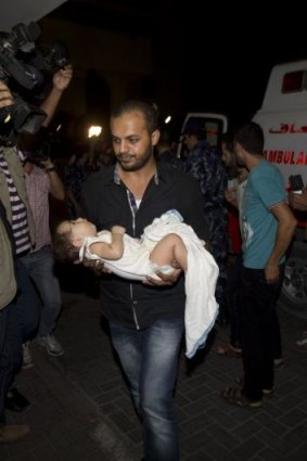 A Palestinian carries a wounded baby into Gaza City's Shifa hospital.