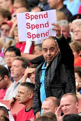 An Arsenal fan holds up a poster bearing the message "spend, spend, spend" to Arsenal's French manager Arsene Wenger during the English Premier League football match between Arsenal and Aston Villa at the Emirates stadium in North London.