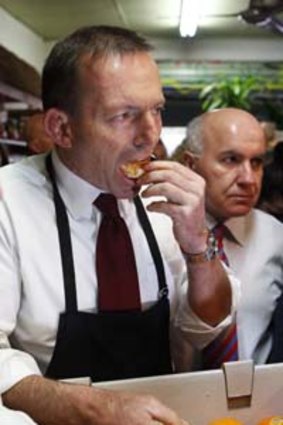 Opposition Leader Tony Abbott eats an easy peel orange during a visit to Fruit World fruit and vegetables shop in the marginal seat of Deakin.