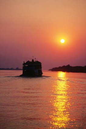 A passing ferry at sunset on Irrawaddy River, Myanmar.