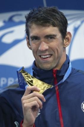 Michael Phelps holds up his men's 100m butterfly gold medal.