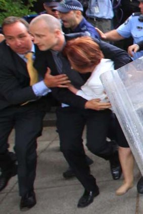 Prime Minister Julia Gillard is dragged away by her close protection team police to her car.