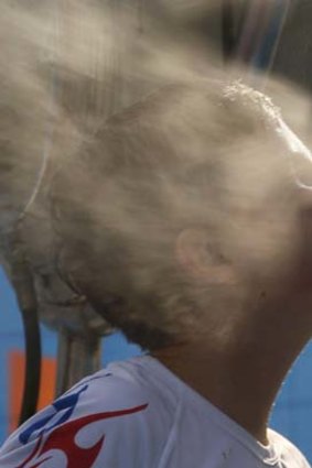 A boy places his face close to the nozzles of a misting fan at the Australian Open.