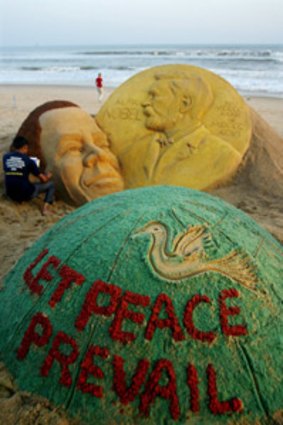 Indian artist Sudarsan Pattnaik and his sand sculpture of Barack Obama on a beach in Puri, India.