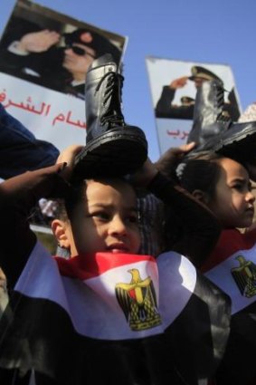 Supporters of Egypt's army chief Field Marshal Abdel Fattah al-Sissi (pictured in portraits), wear Egyptian flags and hold military boots on their heads as a sign of support for military rule.