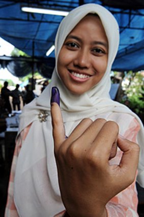 Athia, a 22 year old Indonesian student, shows her inked finger after voting with her family at a polling centre in Jakarta.