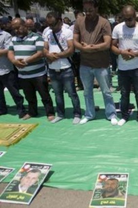 Palestinians pray with images of prisoners before them  during a protest outside Ayalon prison in the Israeli city of Ramleh.