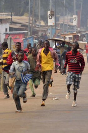 Looters run for cover as they hear rifle shots near the 'Reconciliation crossroad' in Bangui, on January 11, 2014.