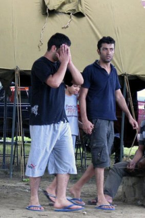 Asylum seekers who survived a wreck walk outside their temporary shelter in Trenggalek, East Java, Indonesia, Sunday, Dec. 18, 2011. Rescuers battled high waves Sunday as they searched for asylum seekers still missing after their wooden ship sank off Indonesia's main island of Java.