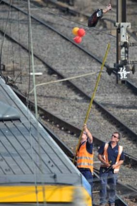 Workers attempt to dislodge the balloons ensnared in overhead power lines between Flinders Street and Southern Cross stations.