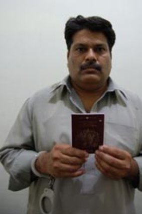 Handcuffed ... Zafar Iqbal holds a fake British passport.