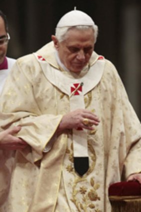 Pope Benedict XVI is assisted after being knocked down by a woman at Christmas Eve Mass.