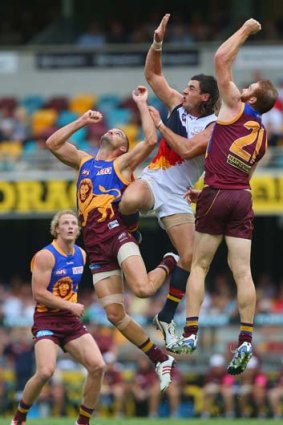 Joel Patful (left) and Daniel Merrett (right) of the Lions and Taylor Walker of the Crows compete for a mark.
