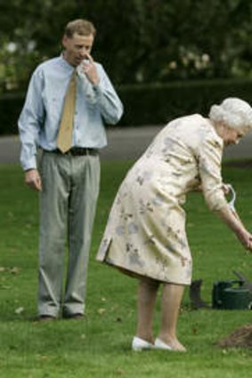 Queen Elizabeth II of Britain is watched by gardener Norm Dunn (left) and her husband Prince Philip (right) as she plants a 'Black Sally' gum tree in the grounds of Government House in Canberra, 2006.