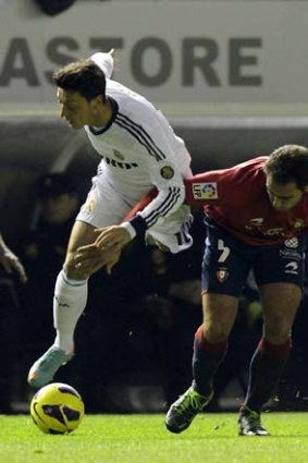 Real Madrid's Mesut Ozil (left) tries to charge past Osasuna's Manuel Jesus Ortiz.