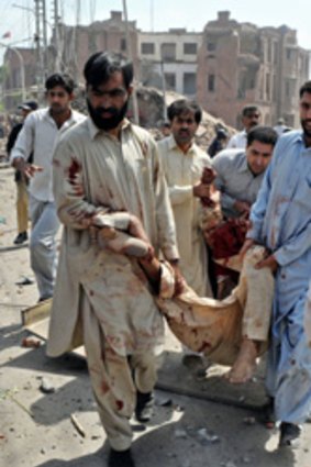Pakistani plainclothes policemen and volunteers carry an injured victim from the rubble of the destroyed police building.