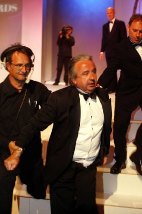 Political journalist Glenn Milne is escorted from the 2006 awards.