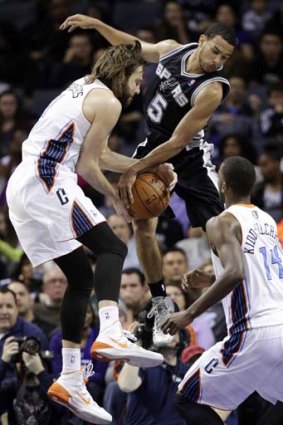 Cory Joseph of the San Antonio Spurs (centre) battles with Josh McRoberts of the Charlotte Bobcats (left) for a rebound as Michael Kidd-Gilchrist of the Bobcats stands nearby.