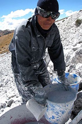 A worker spreads whitewash mortar over the peaks in the Peruvian Andes as part of an experimental plan to save the melting glaciers.