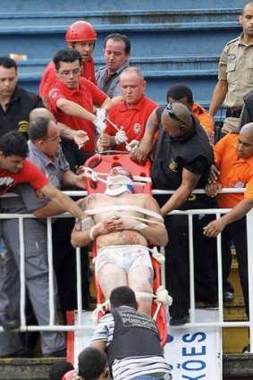 An injured Atletico Paranaense fan is treated after a savage battle on the terraces.