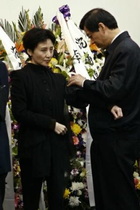 Bo Xilai pins a piece of black cloth on the jacket of his wife Gu Kailai while mourning for his father Bo Yibo.