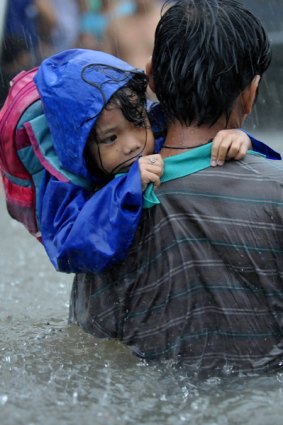 A Filipino girl is carried to safety through floodwaters brought by tropical storm Ketsana in a suburb of Manila.