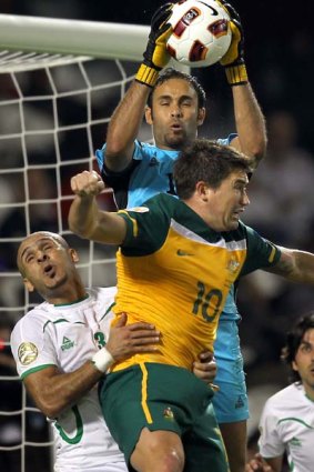 Iraq's goalkeeper Mohammed Qassid (top) catches the ball as defender Bassem Abbas (L) challenges Australia's striker Harry Kewell.