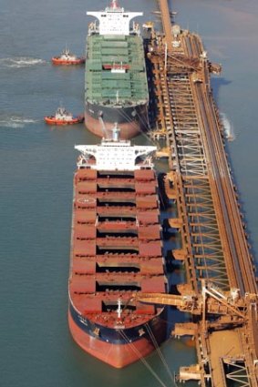 Bulk carriers take on iron ore at a loading facility in Port Hedland.