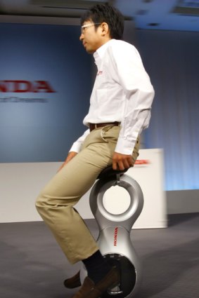A Honda employee demonstrates Honda's new personal mobility device.