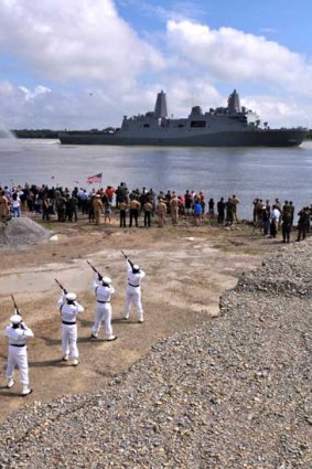 An honour guard at a New Orleans naval base fires a salute to the USS New York as she sails along the Mississippi River.