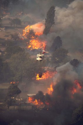 A helicopter waterbombs houses burning at Uriarra at about 1.30pm on January 18, 2003.