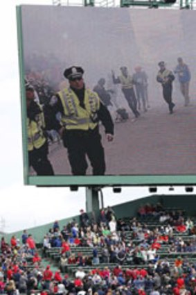 Scenes from the Boston Marathon bombings is displayed on an outfield screen before a baseball game between the Boston Red Sox and the Kansas City Royals in Boston, Saturday, April 20, 2013.
