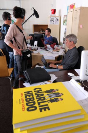 French satirical weekly Charlie Hebdo's publisher and cartoonist, known only as Charb, centre, at work on the controversial issue.