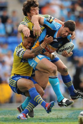 Mark Minichiello of the Titans is tackled by two Eels players.