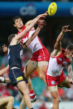 High flyer: Sydney's Kurt Tippett goes up strong against Carlton's Lachie Henderson at the SCG on a soggy Friday night.