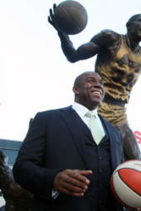 Former Los Angeles Laker Magic Johnson is joined by former Los Angeles Sparks star Lisa Leslie under a statue of Johnson after a news conference at Staples Center in Los Angeles. Johnson is part of a group buying the Sparks.